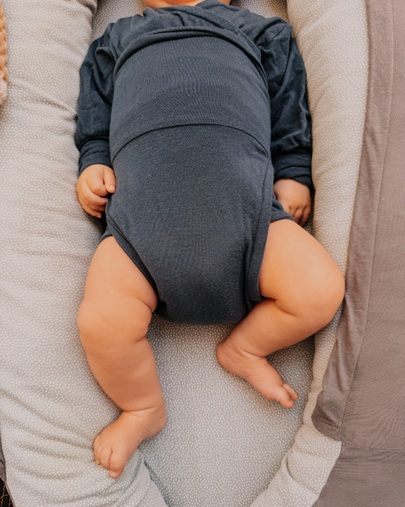 Baby liegt im Nestchen und trägt einen dunkelblauen Loop Body