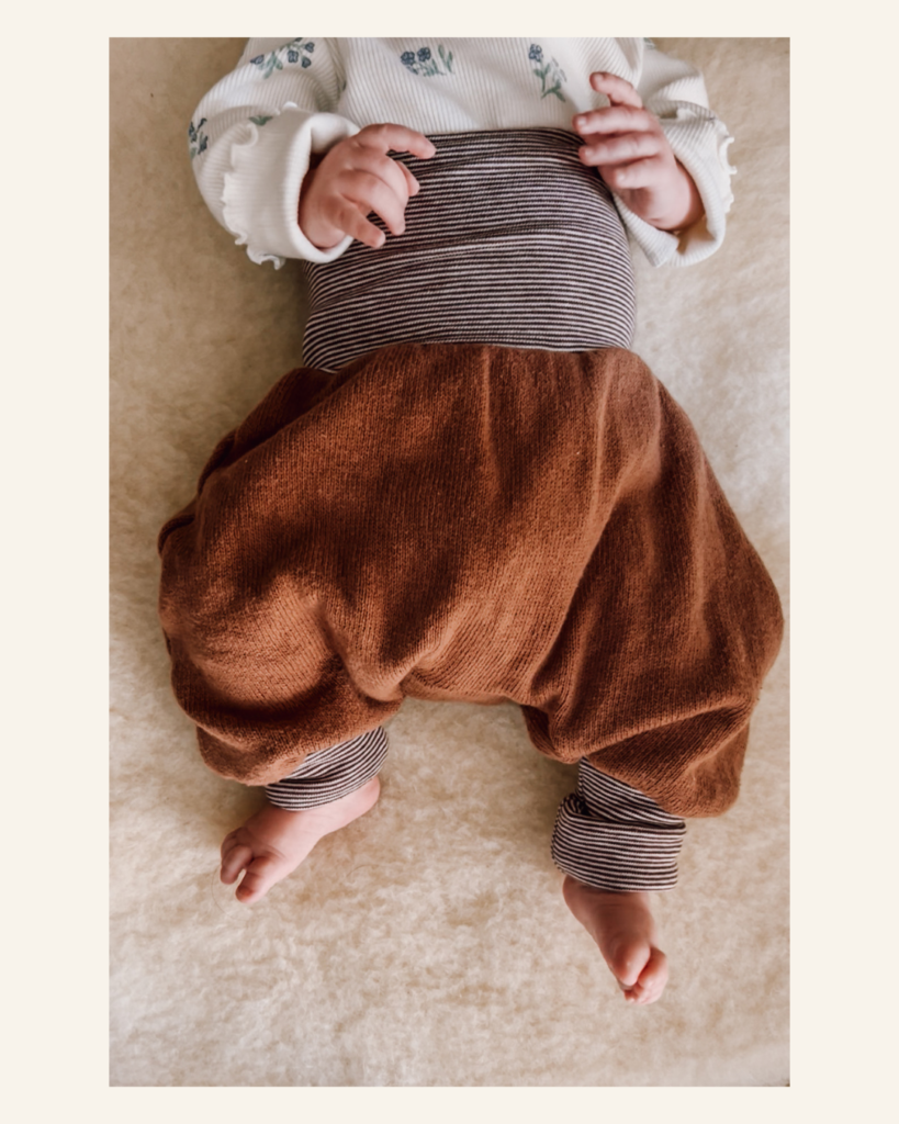 Eine Knickerbocker Mitwachshose von Petit Cochon mit Ringelbündchen, getragen von einem neugeborenen Baby
