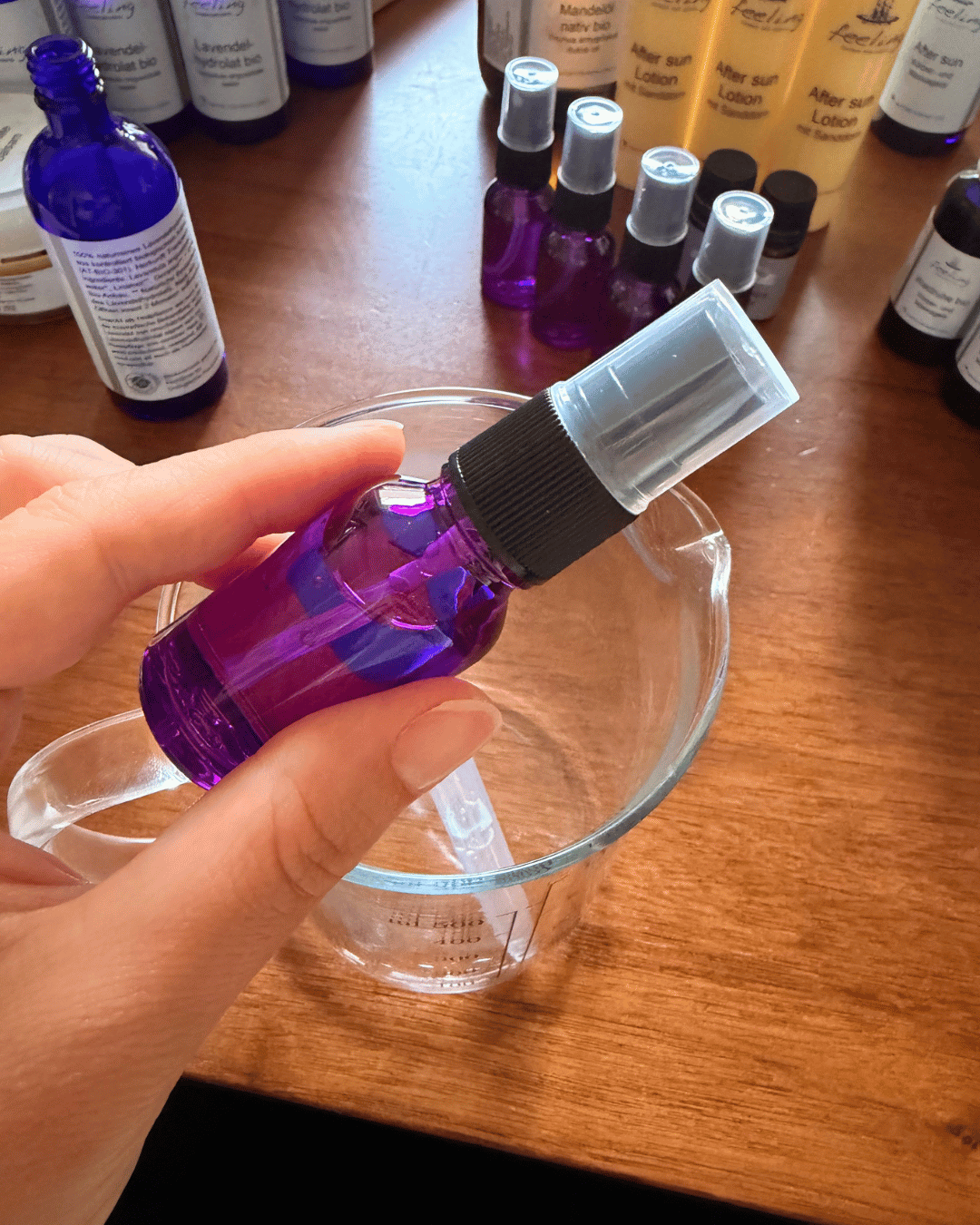 Fläschchen mit Lavendelhydrolat über einem Messbecher (von Hand abgefüllt)