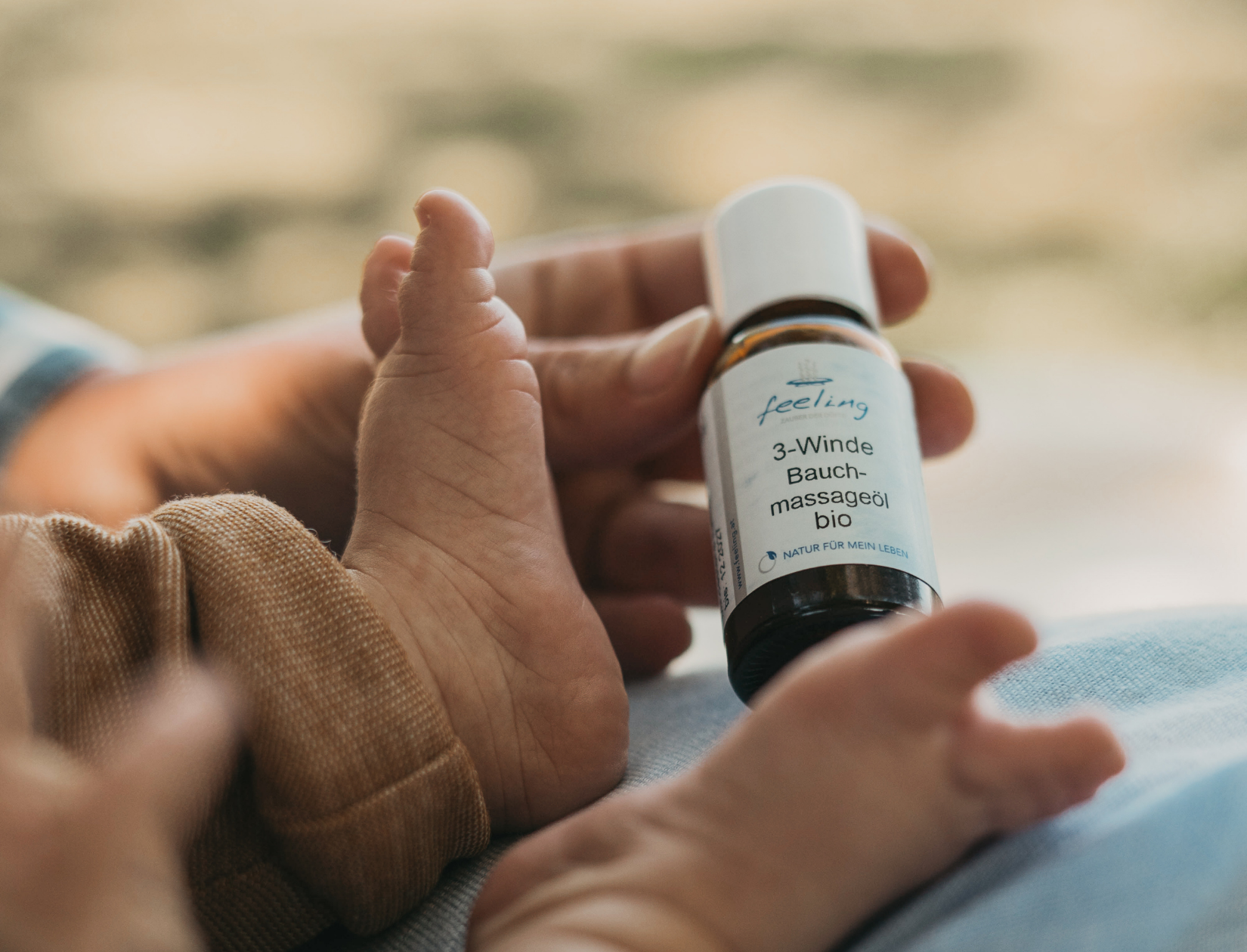 3 Winde Bauchmassageöl bio aus dem Feeling Sortiment, präsentiert neben dem Fuß eines Babys